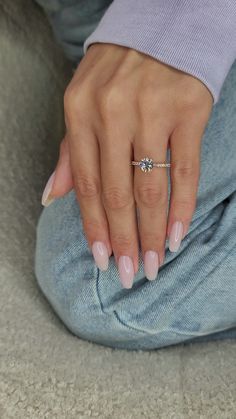 a woman's hand with pink nails and a ring on her left hand, sitting on the floor