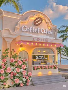 a coffee shop with pink roses in front of it and the ocean in the background