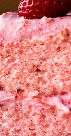 a close up of a slice of cake with strawberries on the top and side