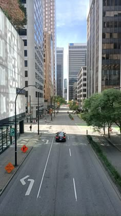 a car driving down an empty street with tall buildings in the backgrouds