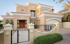 a large house with a gate in front of it and palm trees around the entrance