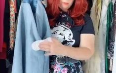 a woman with red hair is looking at clothes