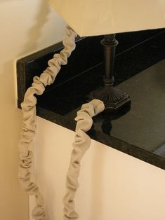 a mirror that has some kind of rope attached to the side of it and is hanging on a wall