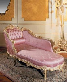 a pink couch sitting on top of a rug next to a mirror