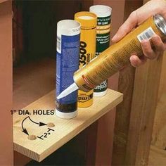 a person holding a spray bottle on top of a wooden shelf next to other items