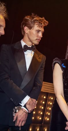 a man in a tuxedo standing next to a woman wearing a black dress