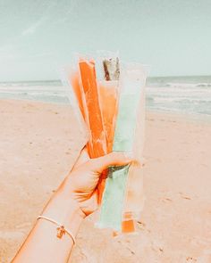 a person holding up some candy on the beach