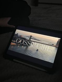 a person holding an electronic device with the word gossip girl on it's screen