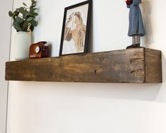 a wooden shelf with pictures and figurines sitting on it's sides next to a potted plant