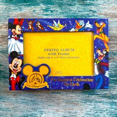 a mickey mouse photo frame with an image of pluto and friends in the background on a wooden table