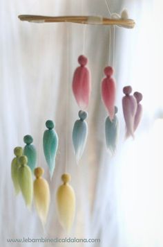 a group of small colorful birds hanging from a wooden stick in front of a window