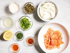 an assortment of ingredients are arranged on a table top, including salmon and capers