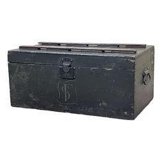 an old black trunk with the letter p on it's lid and handles is shown