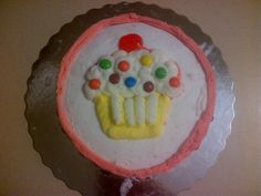 a birthday cake with white frosting and colorful candies on the icing is displayed