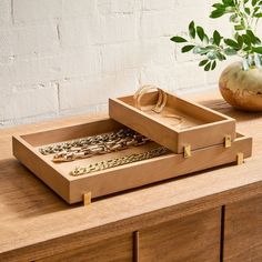 two wooden trays sitting on top of a table next to a potted plant