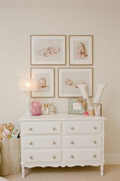 a white dresser with pictures on the wall above it