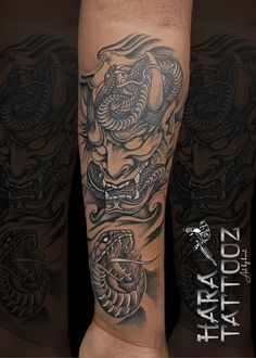 an arm tattoo with a dragon and snake on it