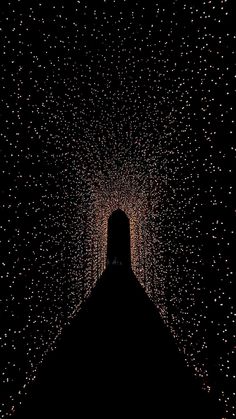 the silhouette of a person standing in front of a tunnel filled with lights at night