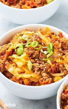 two white bowls filled with food on top of a table