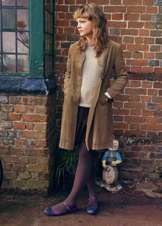 a woman standing in front of a brick wall with her hands on her hips wearing purple socks