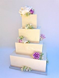 a three tiered cake with flowers on it's sides and white frosting