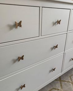 a white dresser with gold butterflies on the handles and drawer knobs, in a living room