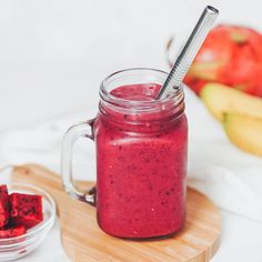 a smoothie in a mason jar with a straw sticking out of it and some fruit on the side