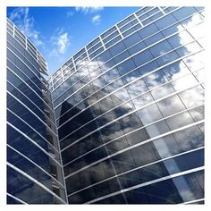 two tall buildings with windows and clouds in the background