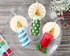 three decorated candles sitting on top of a glass plate next to christmas decorations and candy