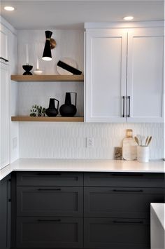 black and white kitchen with open shelving above the countertop, candles on shelves