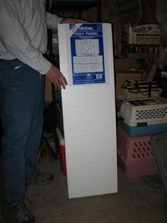 a man standing next to a tall mattress in a room filled with boxes and other items