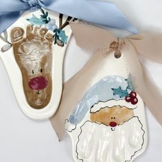 two ceramic christmas ornaments are hanging on the wall next to each other, one with a handprinted santa's shoe