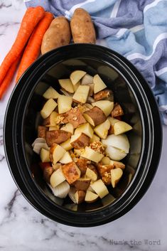 potatoes and carrots in a slow cooker on a marble counter top next to a blue towel