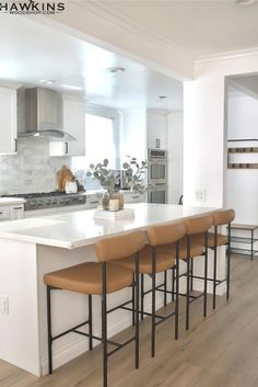 a kitchen island with four stools in front of it