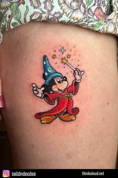 a cartoon character tattoo on the side of a woman's thigh, with stars and a wizard hat