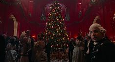 a christmas tree is in the middle of a room with many people standing around it