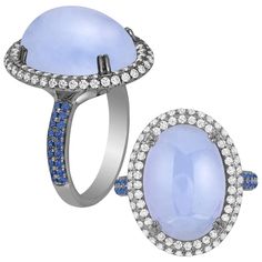 This Blue Chalcedony Cabochon Ring with Diamonds and Blue Sapphire is a stunning piece of jewelry from the 'Limited Edition' Collection. Crafted from 18k white gold and accented with light black rhodium, the ring features a cabochon cut blue chalcedony stone surrounded by sparkling diamonds and blue sapphires on the shank. The combination of the soft blue chalcedony with the bold contrast of diamonds and blue sapphires creates a striking and unique look that is sure to turn heads. Perfect for a special occasion or as a statement piece, this ring is a must-have for any jewelry collection. * Gemstone size: 21 x 17 mm * Gemstone: 100% Earth Mined * Approx. gemstone Weight: 27.72 Carats & Sapphire: 0.32 Carats * 100% Natural Earth-Mined Diamonds * Carat: Approx.: 0.70 Carats * Color: G/H * Cla Sapphire Cocktail Ring, Chalcedony Stone, Contemporary Ring, Diamond Cocktail Rings, Cabochon Ring, Light Black, Black Rhodium, Blue Chalcedony, Oval Cabochon