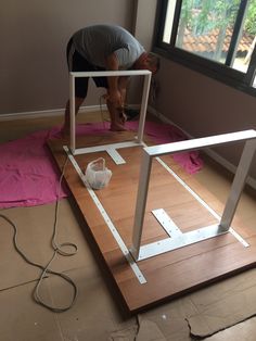 a man is working on an unfinished dollhouse in the middle of a living room