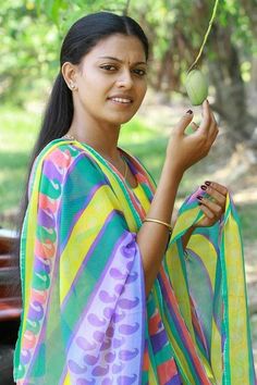 a woman holding an apple in her hand and wearing a colorful sari over her shoulder