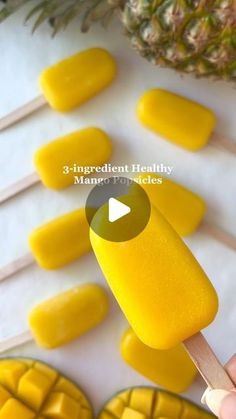 a person is holding a popsicle with pineapples in the background and text overlay that reads 3 ingredient healthy mango popsicles