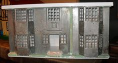 a doll house made out of tin with windows and shutters on the front door