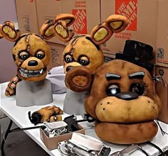 three stuffed animals sitting on top of a white table next to boxes and scissors in front of them