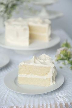 two slices of white cake sitting on top of a table next to plates with flowers