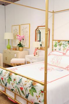 a white bed sitting in a bedroom next to a dresser and mirror with flowers on it