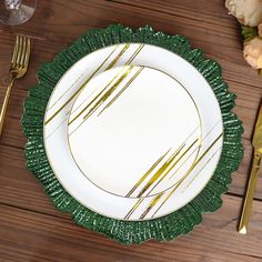 a white plate with gold lines on it sitting next to a fork and silverware