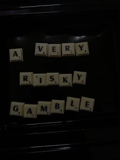 scrabble tiles spelling the words very, risky, game, gambling on a black background