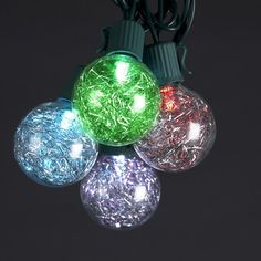 multi - colored christmas lights on black background with white and green balls in the middle