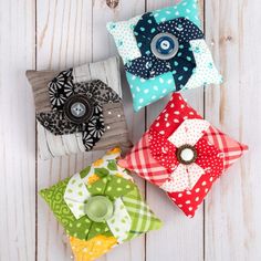 four small decorative pillows sitting on top of a white wooden floor next to each other