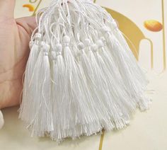 a hand holding a white tassel on top of a table