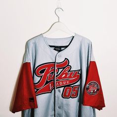 a baseball jersey hanging on a hanger in front of a white wall with red and black lettering